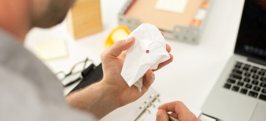 Blut in einem Zellstoff Taschentuch das vom Nasenbluten kommt.